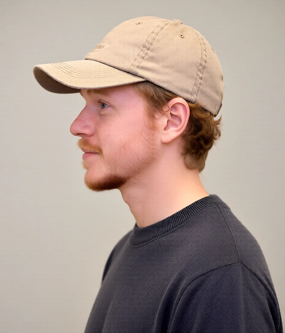 Profile portrait of Tyler wearing a beige cap
